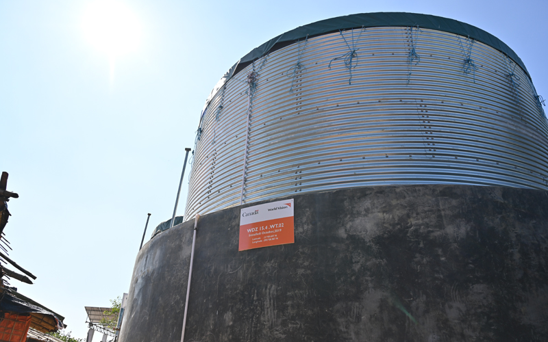 a corrugated metal water tank with a small orange sign on it