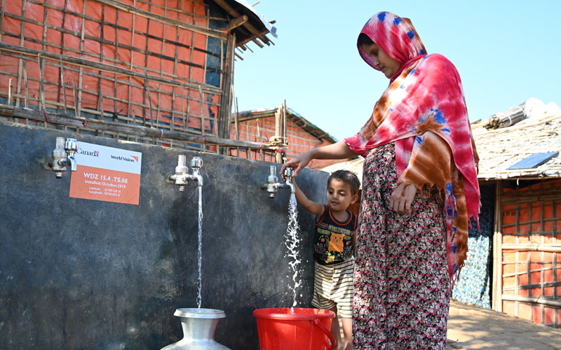 a Rohingya woman gets clean water from a well with her son