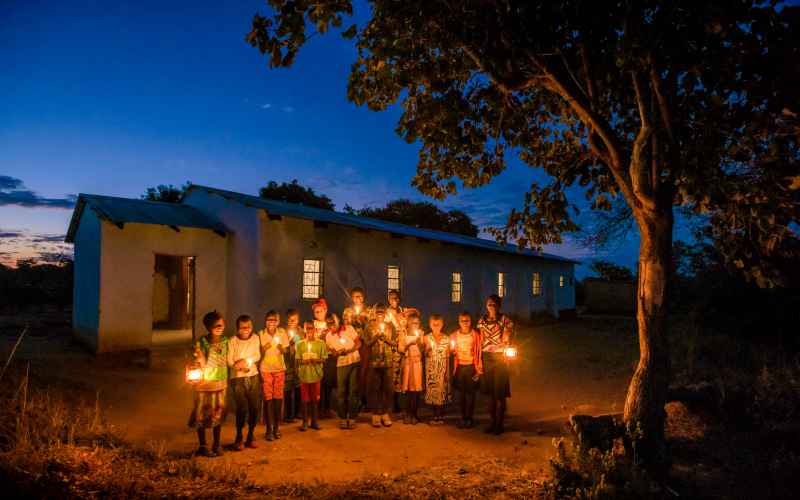 A group of children hold candles at night-time