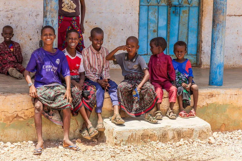 A group of children in Somalia smile for a photo while sitting on a step.