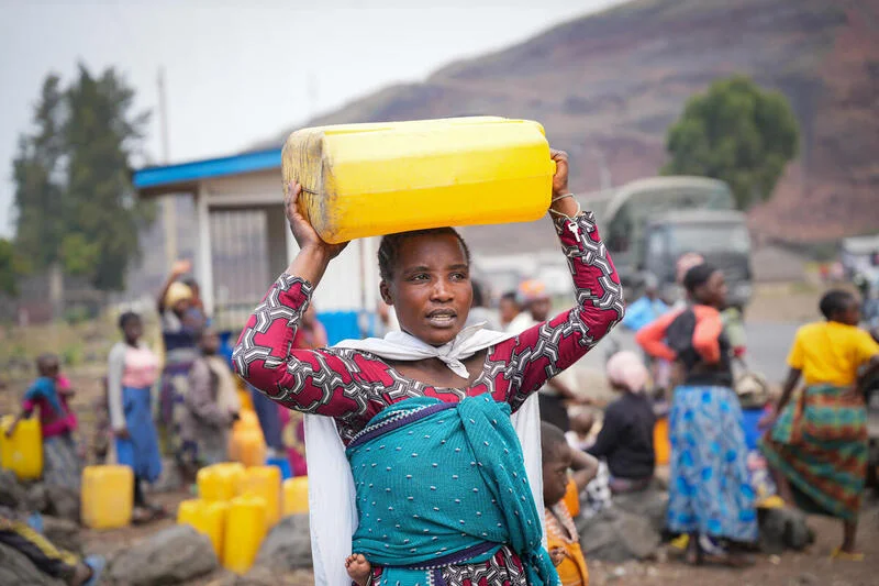 Florance carries water she received from a World Vision response program in the DRC.