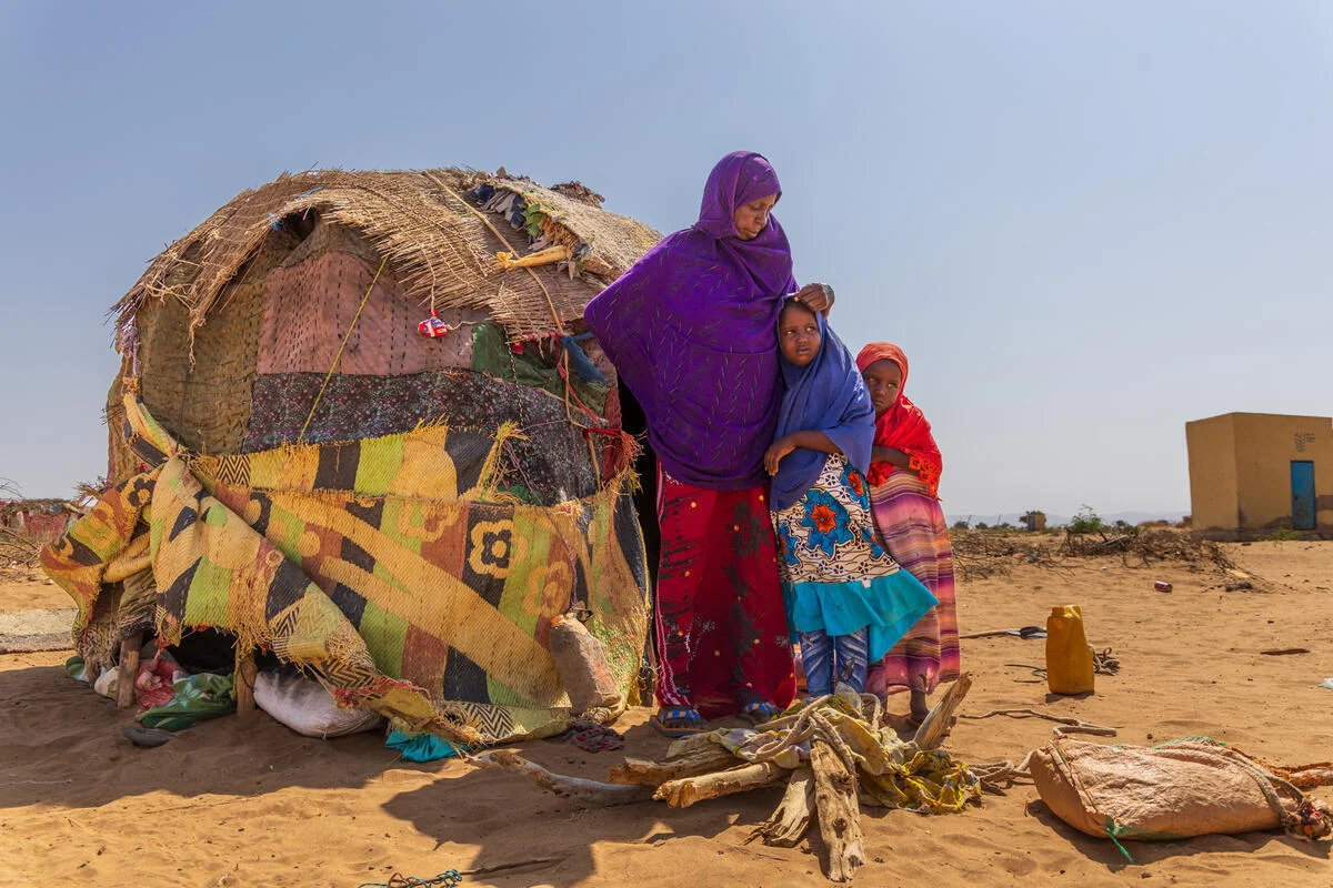 Outside their shelter, a grandmother in Somalia hugs her granddaughters.