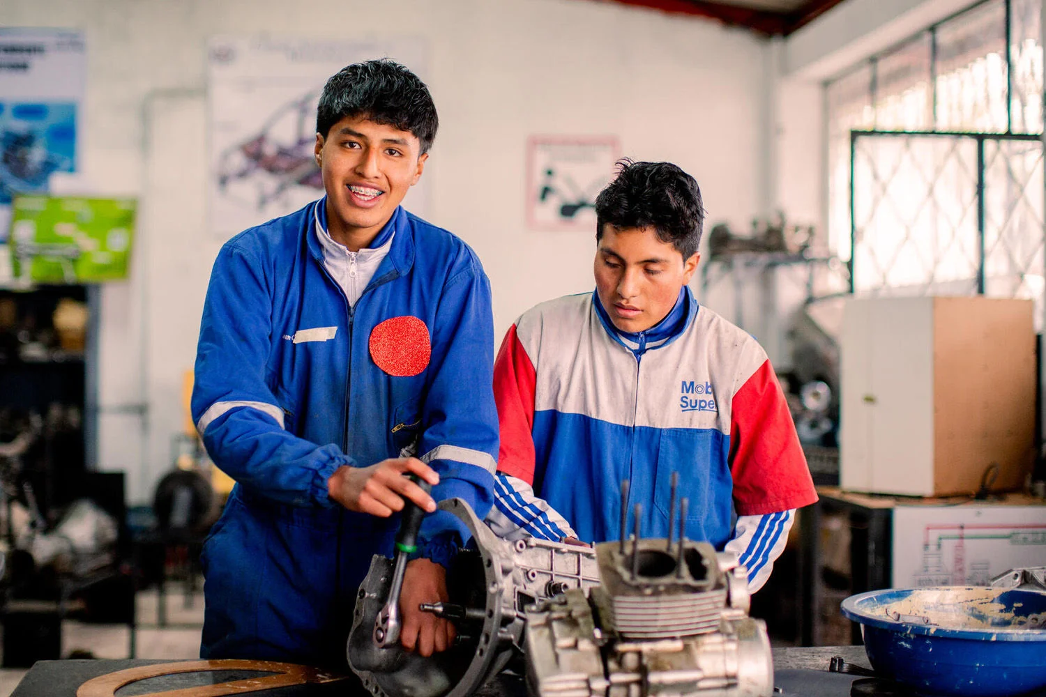 Youth Ready Participant Oliver works on his clothing printing machine with a friend 