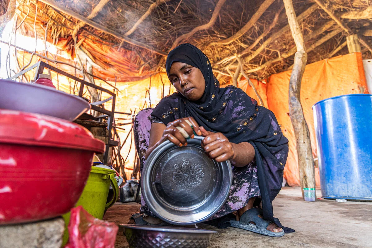 A girl washes dishes inside her family’s makeshift shelter in a refugee camp in Somalia.