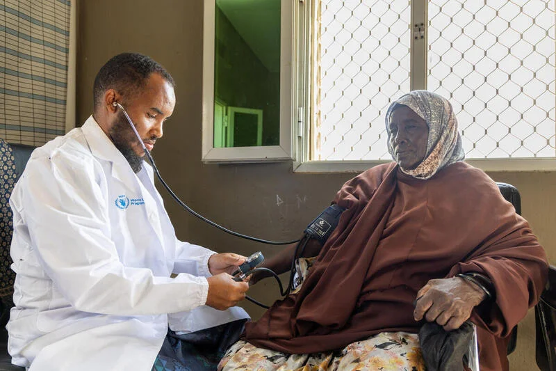 A women sitting in a health clinic in Somalia has her blood pressure checked by a doctor.