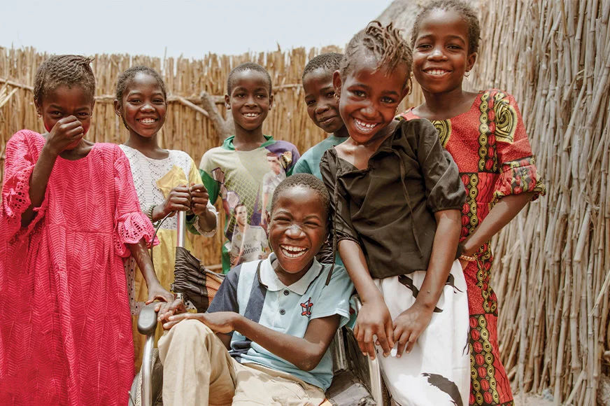 Boubakar (centre) was born with a disability and could not walk. Now, Boubakar has more mobility and can play with his friends, thanks to the wheelchair provided by his sponsor. (Senegal, 2025)