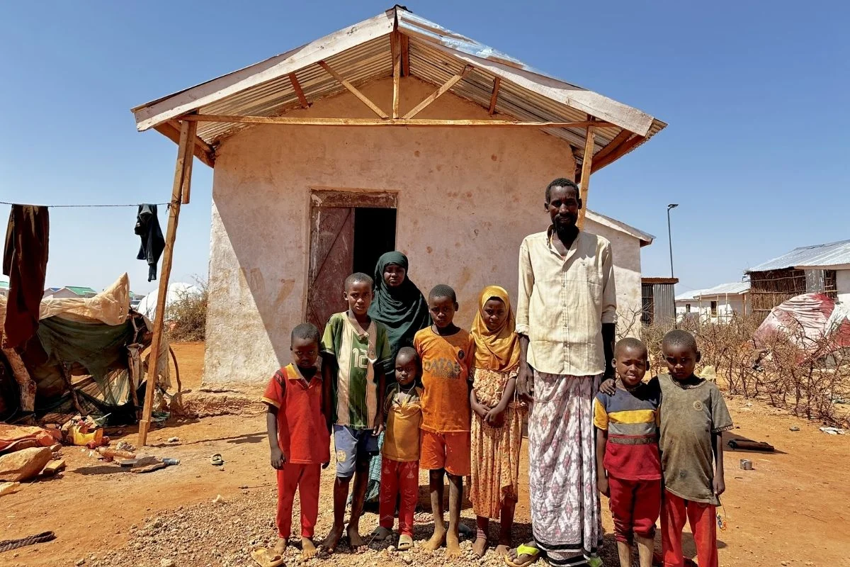 A man with his children stand outside their home in an internal displacement camp in Somalia.