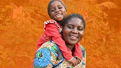 A smiling mother carries her daughter on her shoulders.