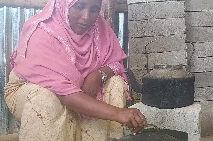 A woman shows a finished, ready-to-use energy-efficient cookstove.