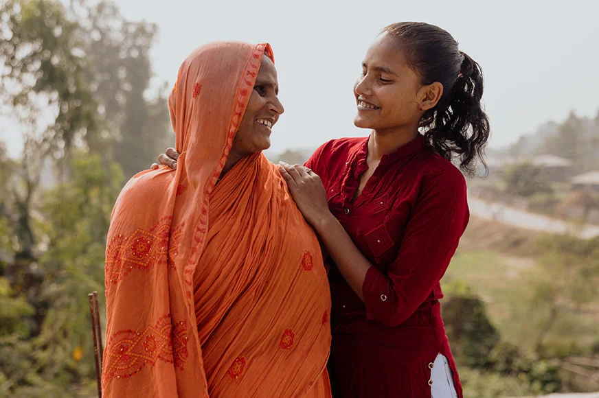Neha, a peer leader in her community, looks and smiles at her mother.
