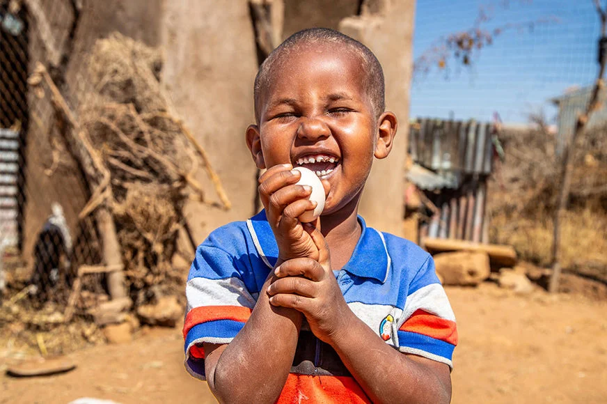 Risaaq, 5, holds an egg from the chickens that World Vision provided, ensuring his family’s continued access to food and income. Eggs improve nutrition, particularly for growing girls and boys.