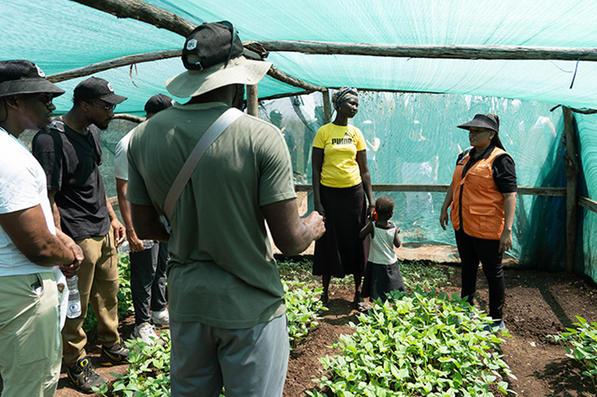 A World Vision staff speaks to football players in a community garden outside Kakuma. (Kenya, 2024)