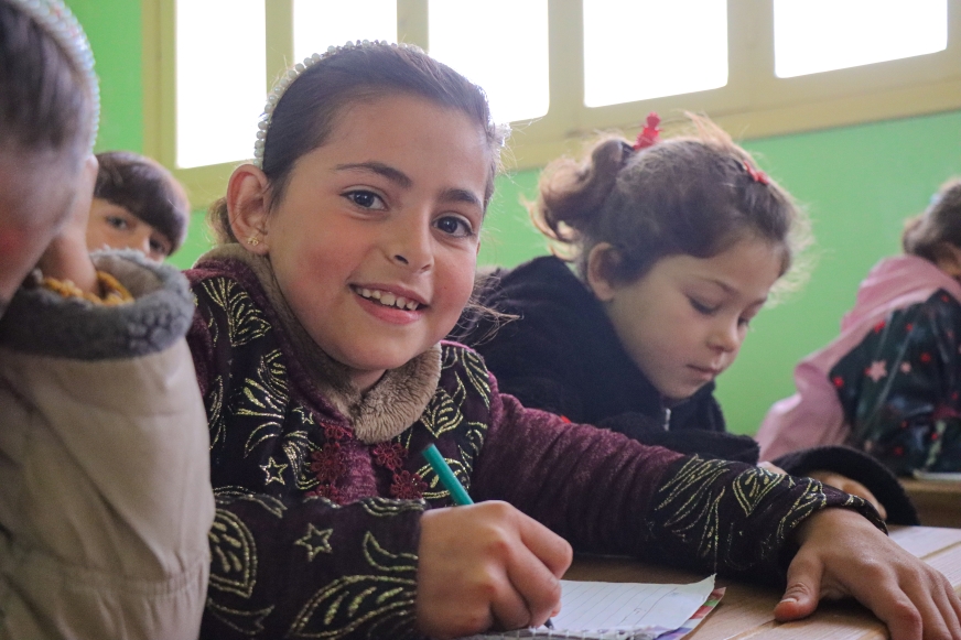 Firyal sits among her classmates at school and smiles. Syria