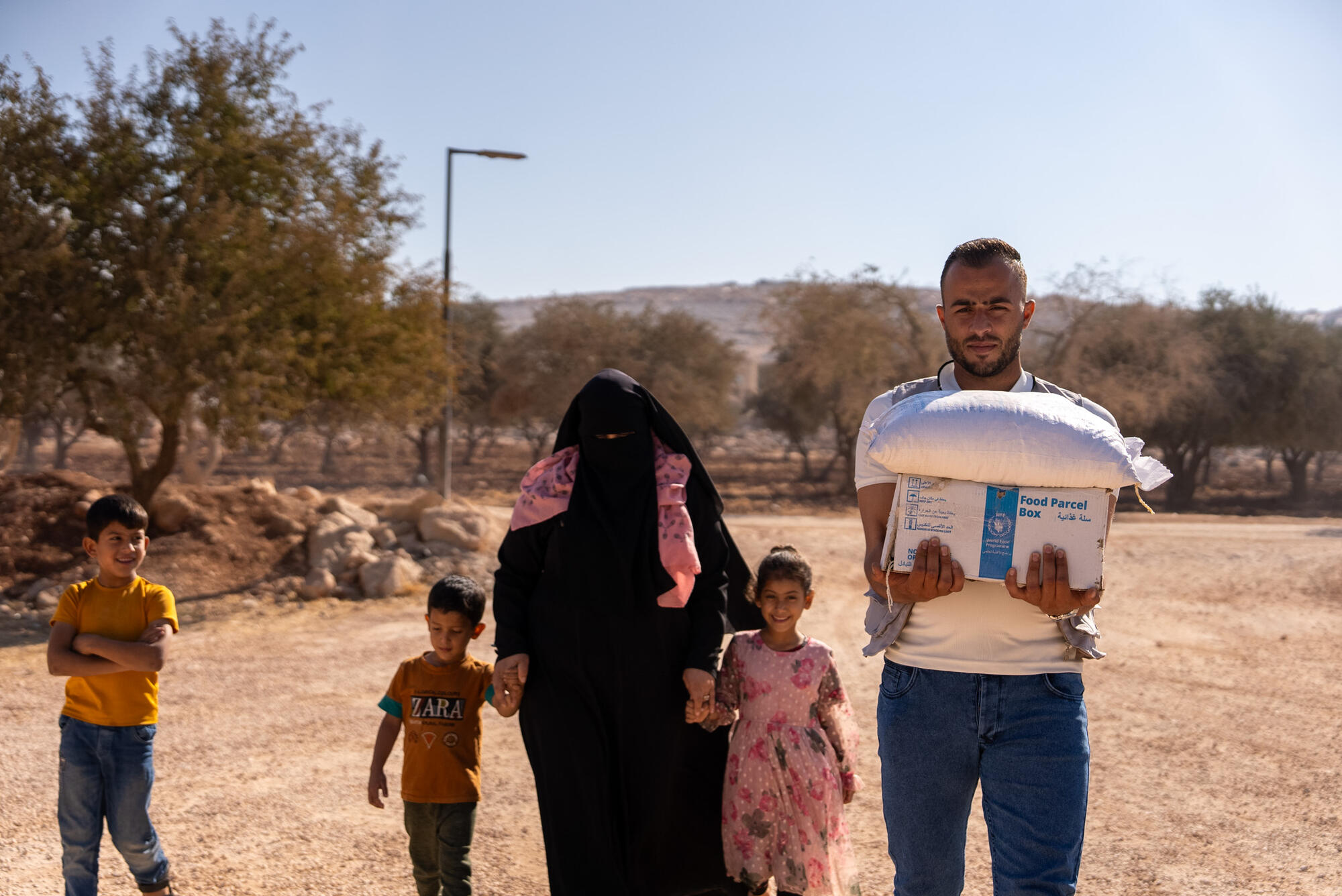 A World Vision worker delivers the family’s food parcel to their tent.  
