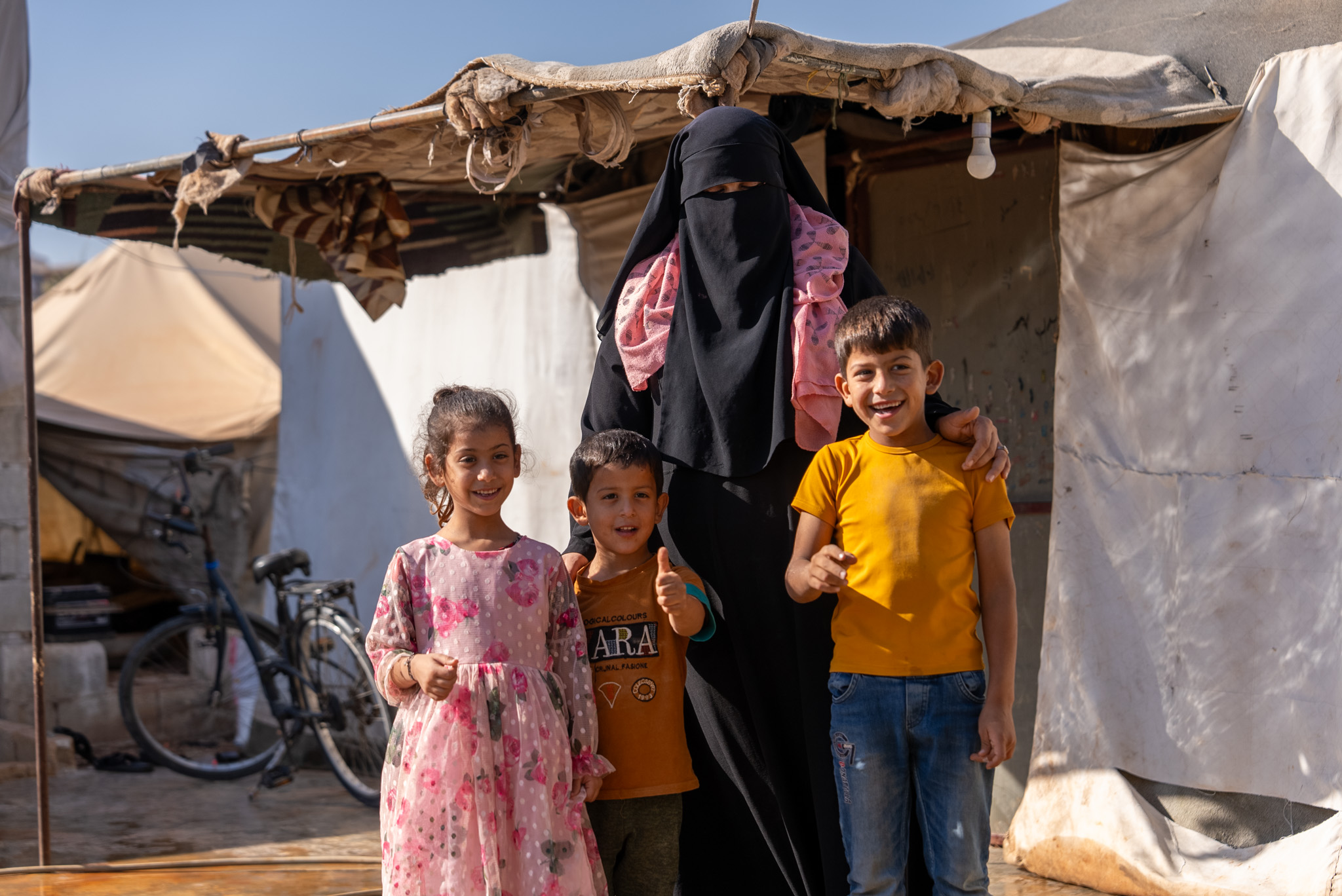 Um Muhammad poses with three of her kids in front of their tent. “All my strength comes from them,” she says. “When I see the love in their eyes, I feel as though I could take on the world for them.” 