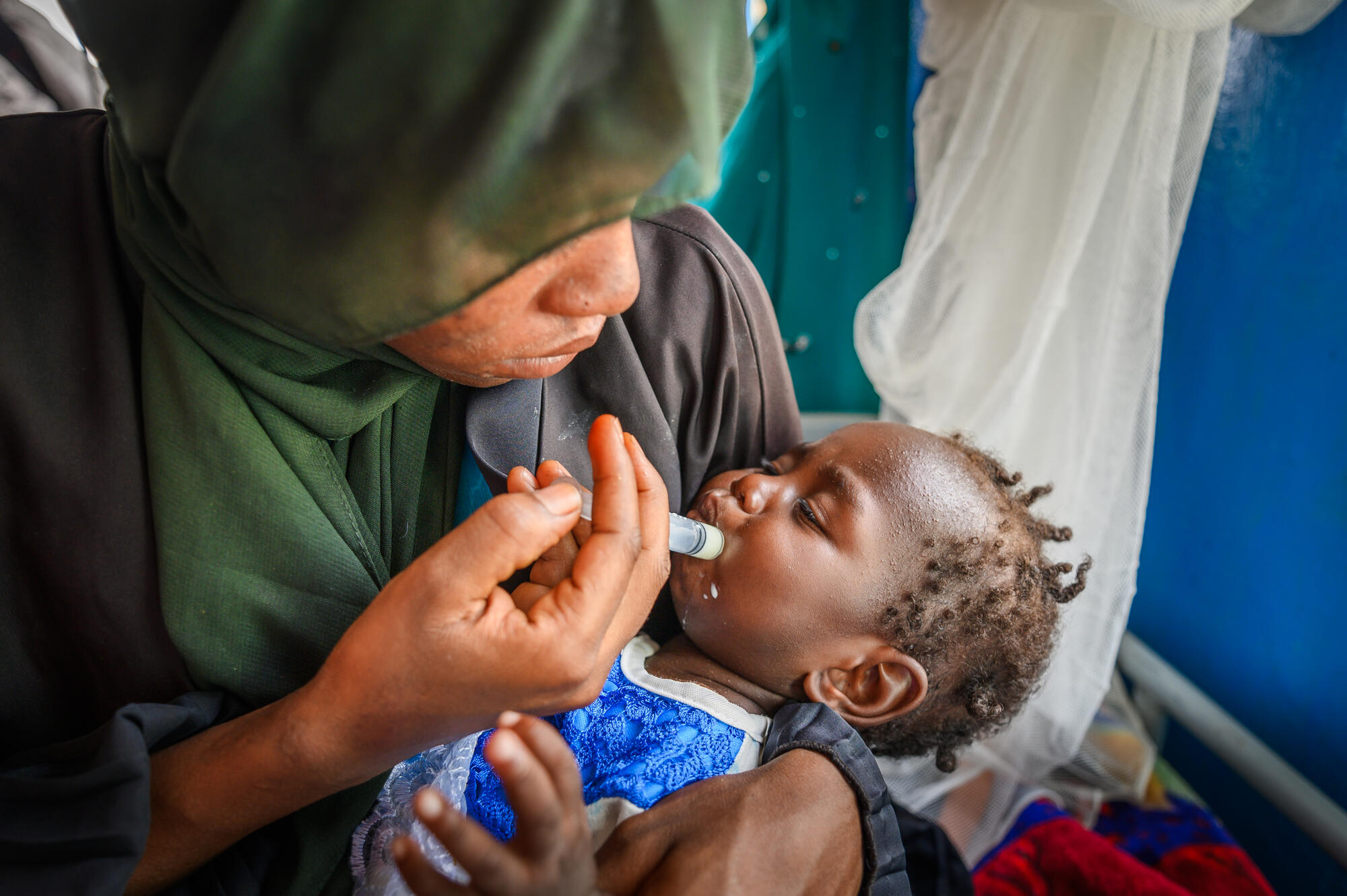 In Chad, a woman feeds her malnourished baby girl using a syringe.  
