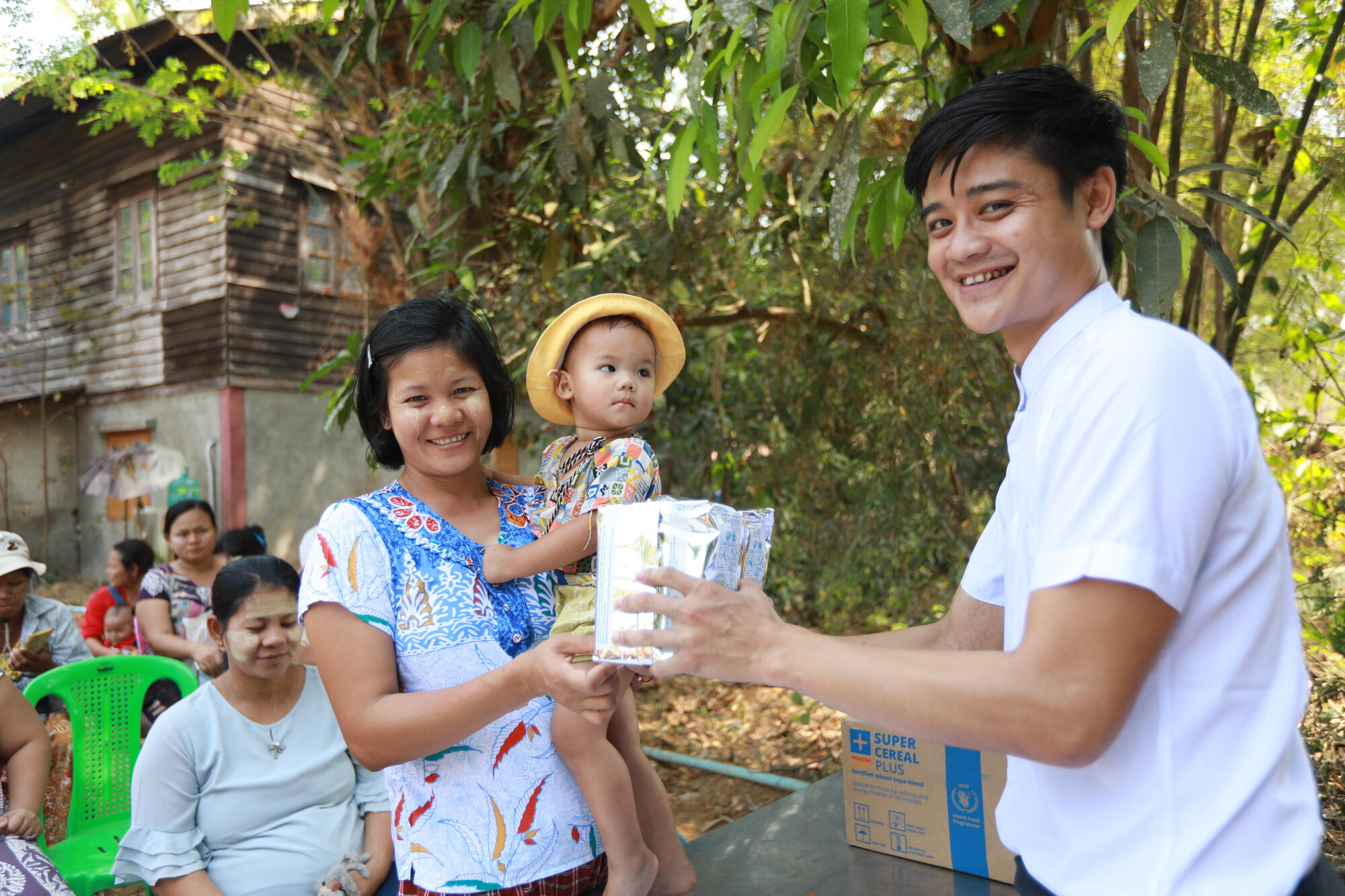 Htoo (right), once a child sponsored through World Vision, is now a staff member. Here, he distributes nutrient-rich porridge formula to families of undernourished children in Myanmar in 2024.  