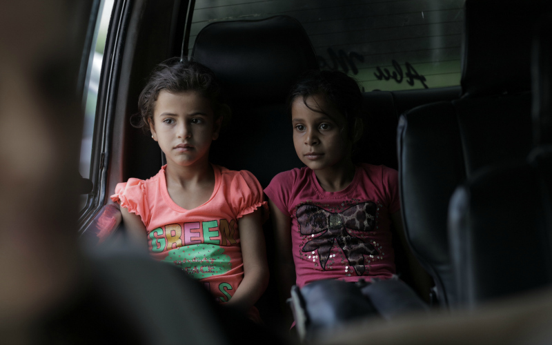 Two Syrian refugee girls inside a car.