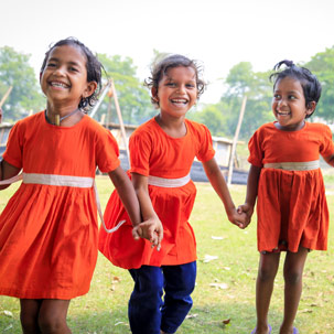 Three small girls wearing red dresses play together holding hands