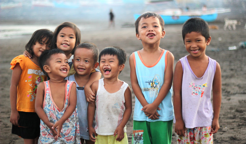 A group of children smiling, laughing and hugging in front of the camera.