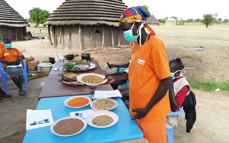 One mother from the mom group in South Sudan stands in front of a table during a practical demonstration.
