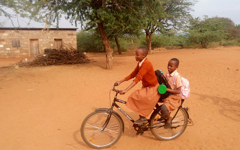 Two girls ride on a bike