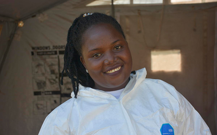 A woman wearing a white hazmat suit smiles in a South Sudanese health facility.