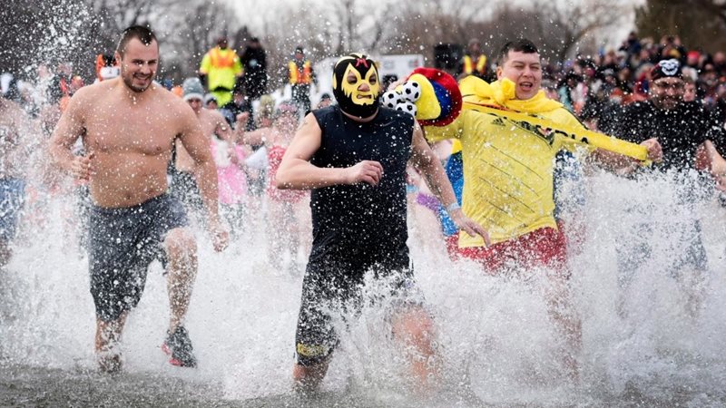 Three men run into the lake during a polar plunge event.