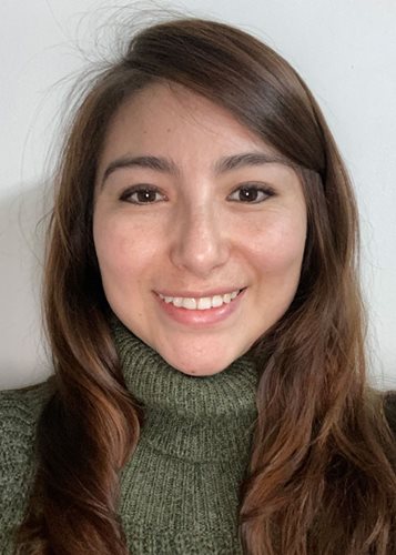 a young Colombian woman smiles at the camera. She wears a green turtleneck