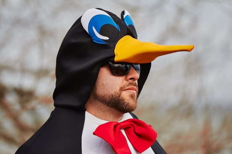 A guy wearing a bird costume and sun glasses.