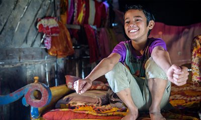 a young child is seen smiling while sitting on a bed in his home