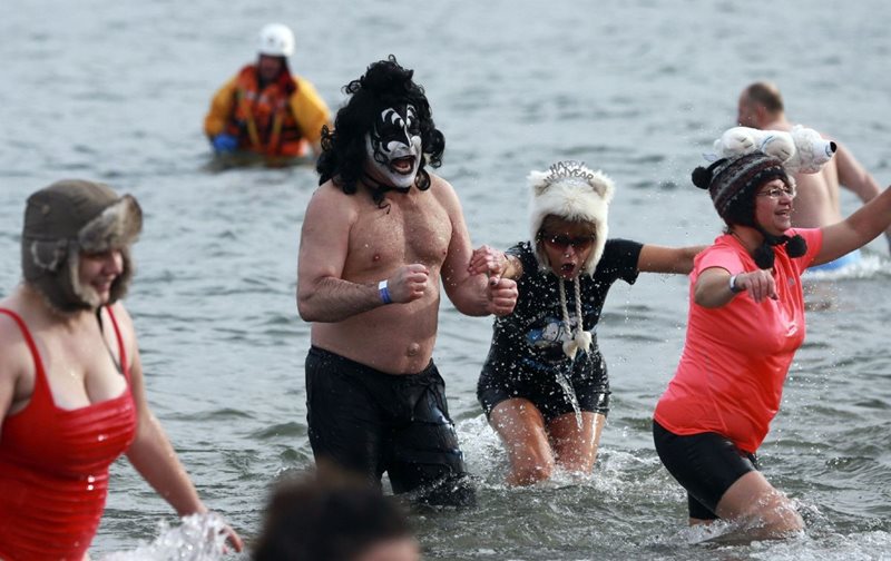 Several people walk out of a cold lake during a polar plunge event.